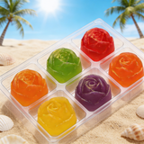 Colorful rose-shaped candies in a transparent container on a sandy beach with palm trees in the background.