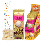 Dible Dough Sugar Cookie with Sprinkles shown as a single foil packet, a display box filled with individual packets, and several stacked cookies with colorful sprinkles on a white background.